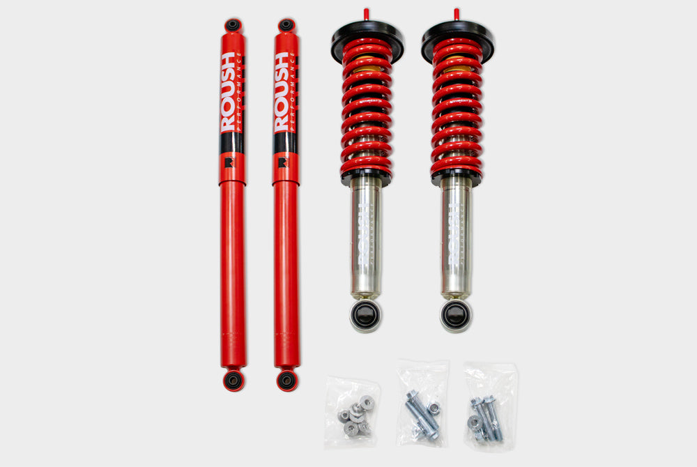 Red shock absorbers and coilover springs set with installation hardware on a white background, designed to enhance off-road capability and elevate F-150 trucks with Roush Performance Suspension.